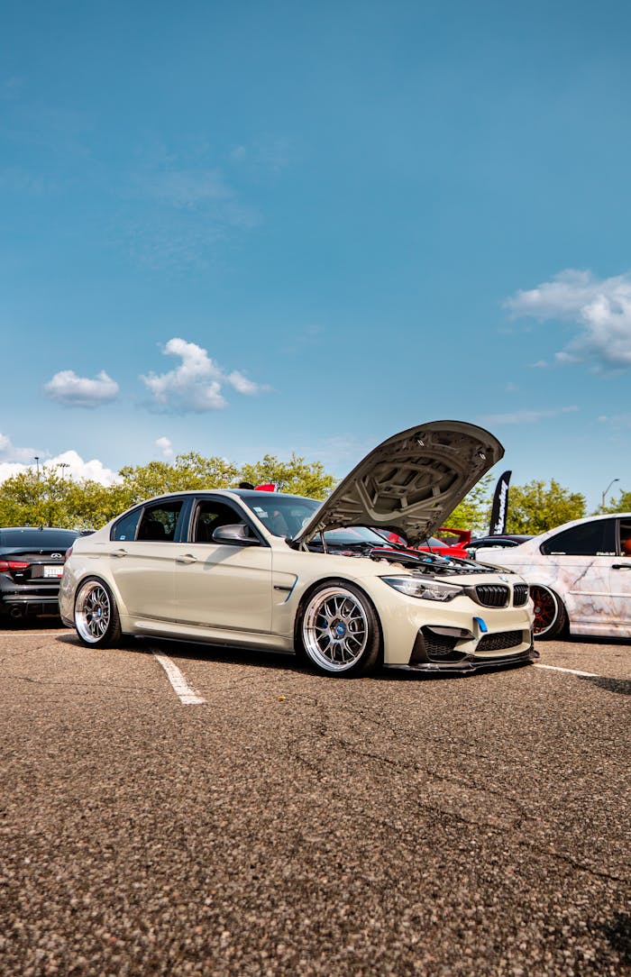 High-performance BMW with open hood at a Toronto car show on a sunny day.